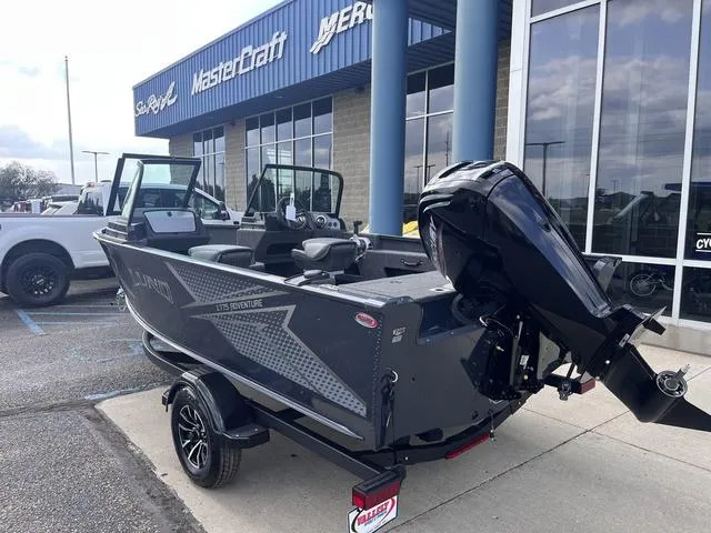 Slide: The Image of 2025 Lund 1775 Adventure Sport boat with outboard motor, parked outside a dealership. - 3