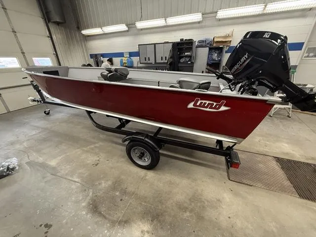 Slide: The Image of 2025 Lund 1600 Fury Tiller boat in a garage, featuring a red exterior and Mercury engine. - 1