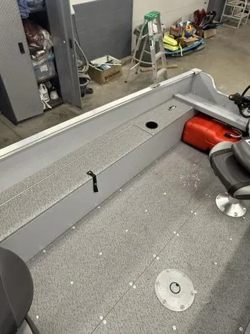Slide: The Image of 2025 Lund 1600 Fury Tiller boat interior with storage, seating, and fuel tank in a garage setting. - 11