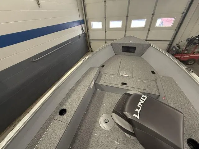 Slide: The Image of 2025 Lund 1600 Fury Tiller boat interior in a garage, showcasing seating and storage. - 16