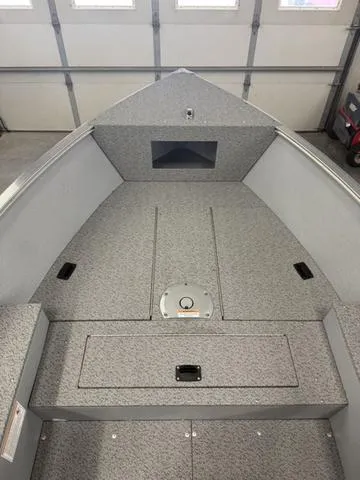 Slide: The Image of 2025 Lund 1600 Fury Tiller boat interior, featuring spacious, carpeted deck in a garage setting. - 17
