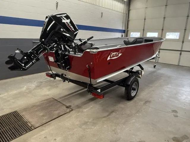 Slide: The Image of 2025 Lund 1600 Fury Tiller boat in garage, red exterior, on trailer. - 4