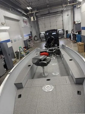 Slide: The Image of 2025 Lund 1600 Fury Tiller boat in a garage, featuring seating and storage compartments. - 7