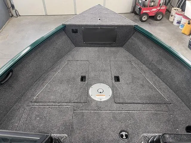 Slide: The Image of 2025 Lund 1650 Rebel XL Sport boat interior with carpeted deck and storage compartments. - 14