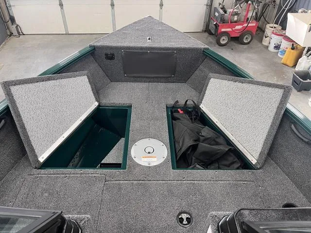 Slide: The Image of 2025 Lund 1650 Rebel XL Sport boat interior with open storage compartments in a garage setting. - 16