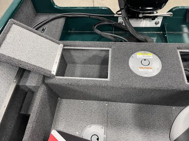 Slide: The Image of 2025 Lund 1650 Rebel XL Sport boat interior with storage compartments and motor cables. - 21