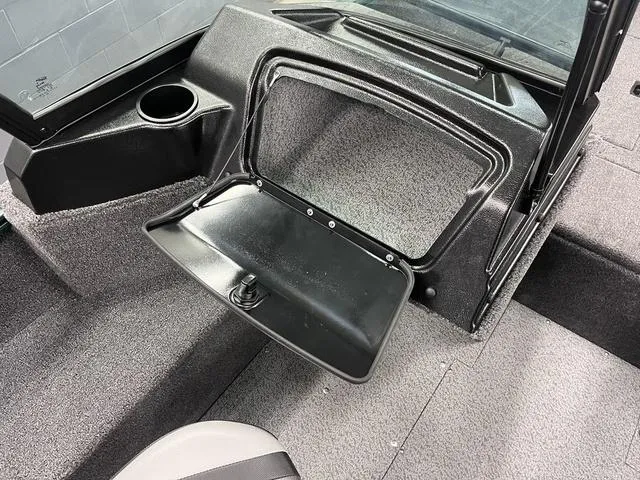 Slide: The Image of 2025 Lund 1650 Rebel XL Sport boat interior with open storage compartment and cup holder. - 9