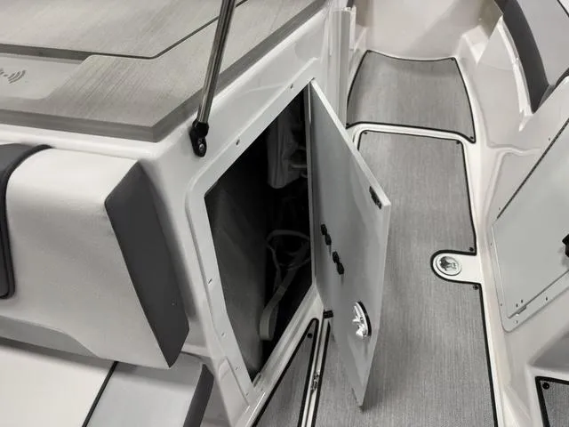 Slide: The Image of 2025 Yamaha Boats AR220 interior storage compartment with open door, showcasing sleek design. - 10
