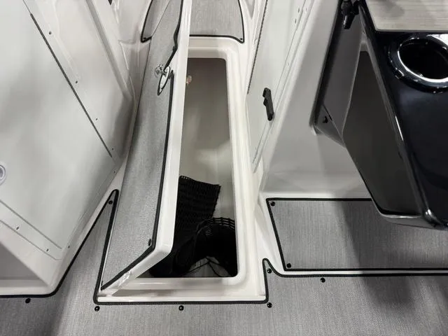 Slide: The Image of 2025 Yamaha AR220 boat storage compartment with open hatch, showcasing interior space and sleek design. - 12
