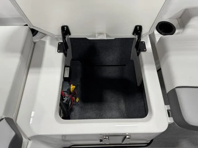 Slide: The Image of 2025 Yamaha Boats AR220 storage compartment with open lid, showcasing interior space and wiring. - 16