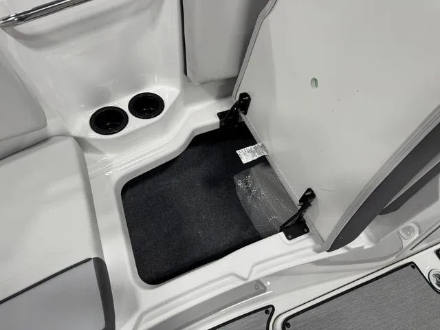 Slide: The Image of 2025 Yamaha AR220 boat storage compartment with open hatch and cup holders. - 23