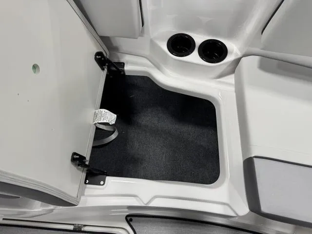 Slide: The Image of 2025 Yamaha Boats AR220 interior storage compartment with open hatch and cup holders. - 24