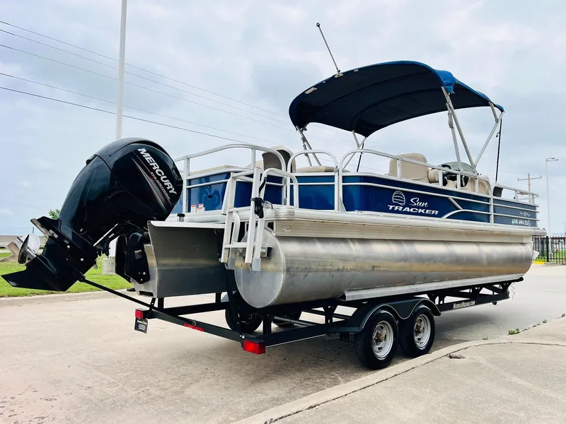 Slide: The Image of 2017 Sun Tracker Fishin' Barge 22 XP3 pontoon boat on trailer, featuring a Mercury outboard motor. - 6