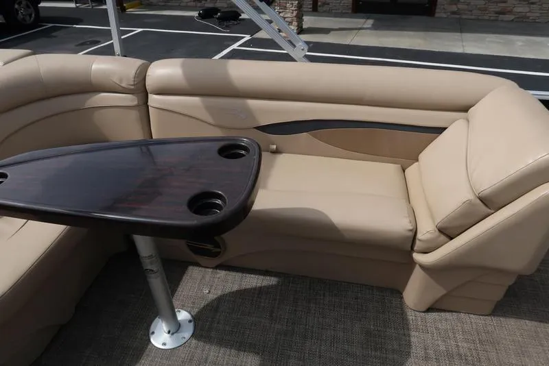 Slide: The Image of 2016 Bennington 22 SLX boat interior with beige seating and a dark wood table. - 16
