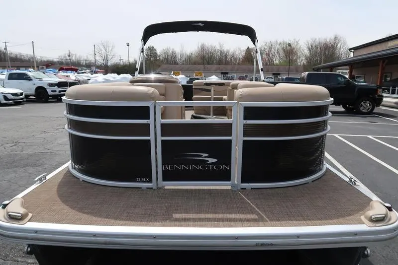 Slide: The Image of 2016 Bennington 22 SLX pontoon boat with beige seating, parked in a lot. - 6