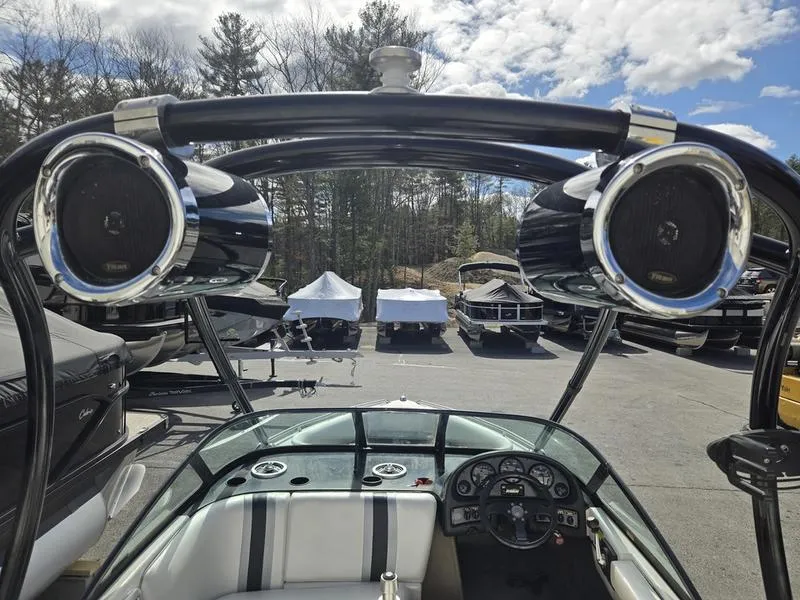 Slide: The Image of 2001 Malibu Sportster boat interior with speakers and dashboard, parked outdoors under a cloudy sky. - 16