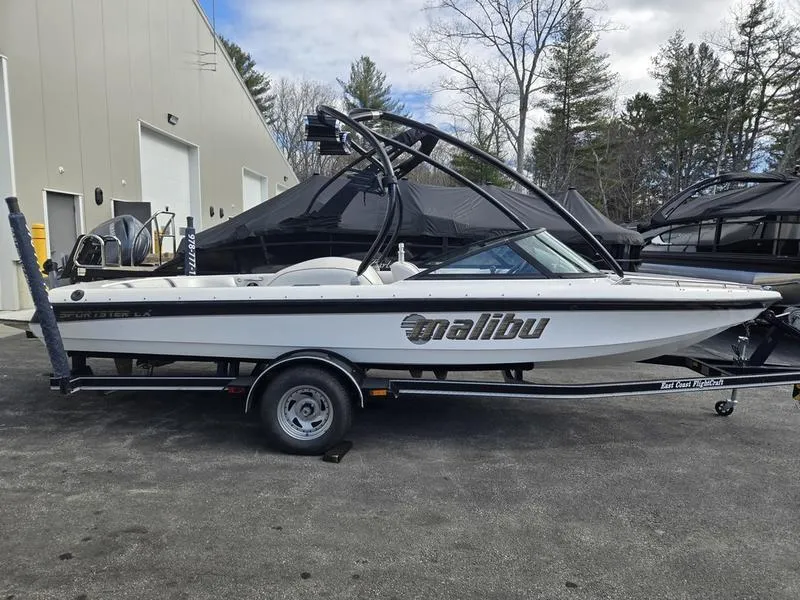 Slide: The Image of 2001 Malibu Sportster boat on trailer, parked outdoors near industrial building. - 3