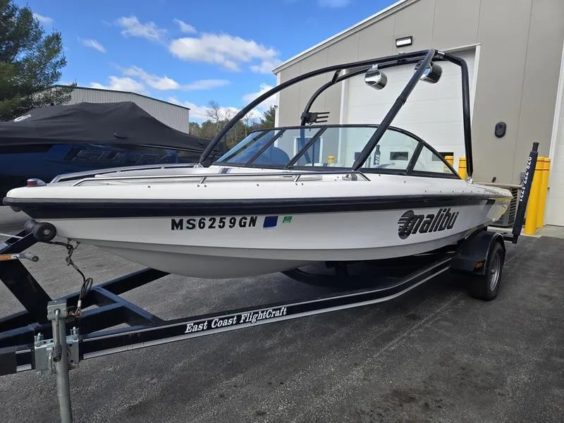 Slide: The Image of 2001 Malibu Sportster boat on trailer, parked outside a building under a clear sky. - 4