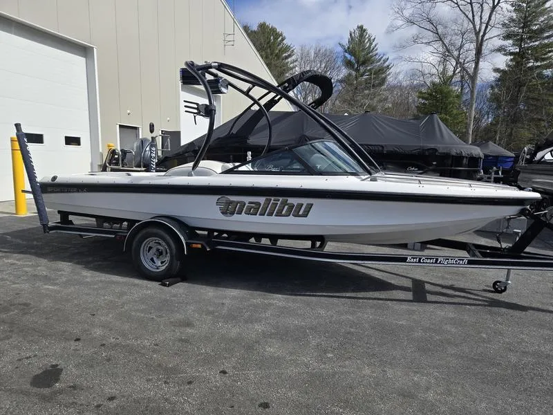 Slide: The Image of 2001 Malibu Sportster boat on trailer, parked outdoors near a building. - 5