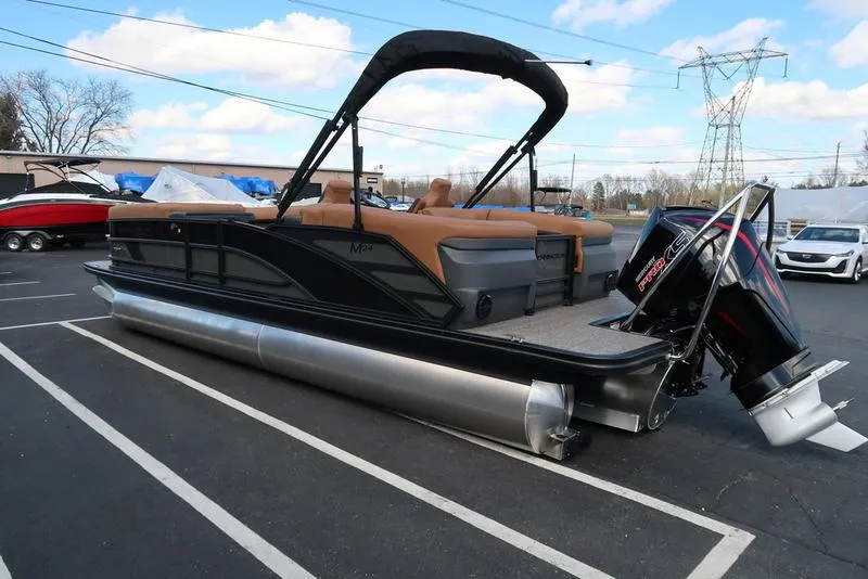 Slide: The Image of 2025 Bennington M Quad Bench 24 MFB pontoon boat with outboard motor in parking lot. - 6