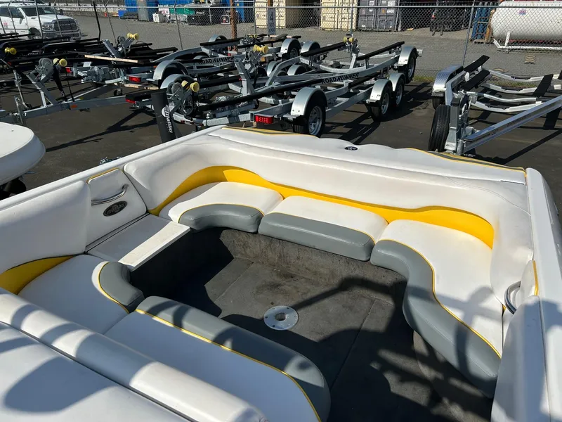 Slide: The Image of 2002 Malibu Wakesetter 21 XTi boat interior with white and yellow seating, parked near trailers. - 7
