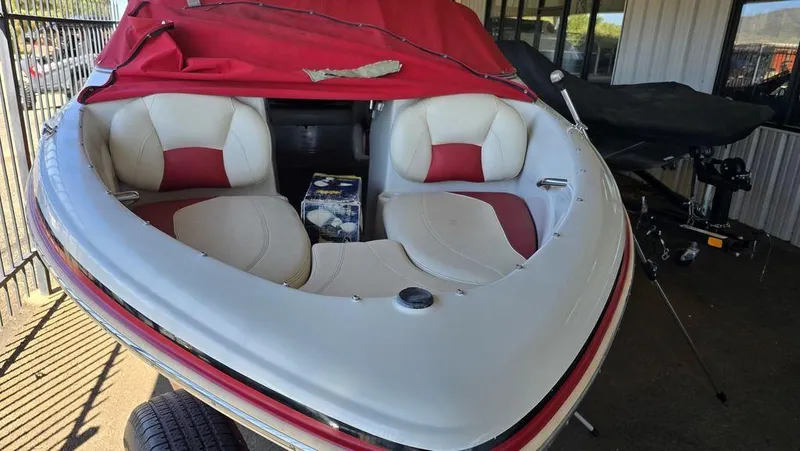Slide: The Image of 2014 Tahoe Q5i boat with red and white interior, covered and parked. - 18