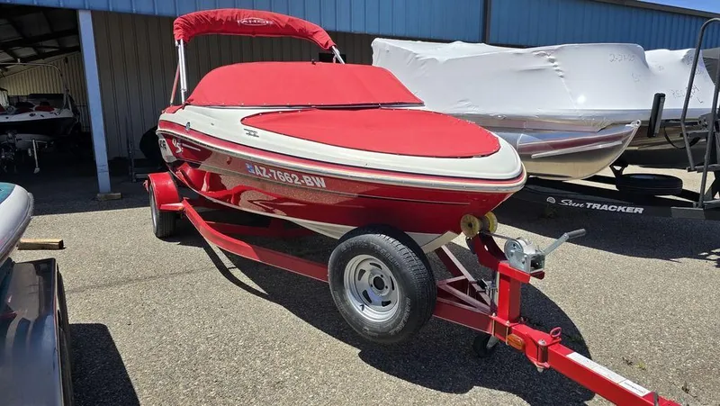 Slide: The Image of 2014 Tahoe Q5i boat with red cover on trailer in storage area. - 2