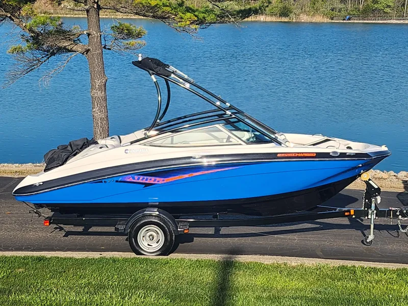 Slide: The Image of 2014 Yamaha Boats AR192, blue and white, on trailer by a lake. - 0