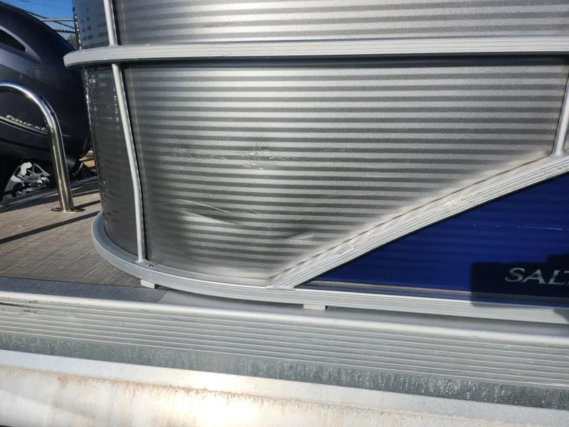 Slide: The Image of 2022 Bennington S 22 L-Bench pontoon boat with visible side panel damage. - 11