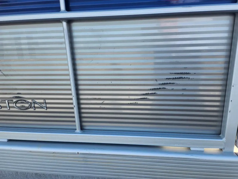 Slide: The Image of 2022 Bennington S 22 L-Bench pontoon with visible scratches on the aluminum siding. - 13