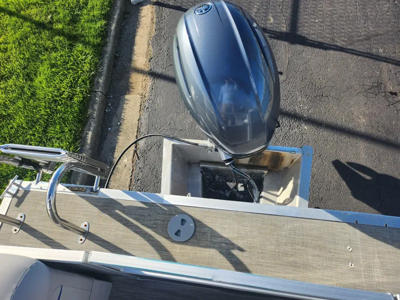 Slide: The Image of 2022 Bennington S 22 L-Bench boat with outboard motor, docked on pavement. - 22