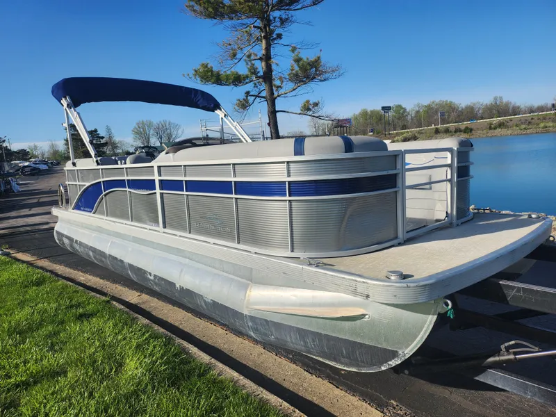 Slide: The Image of 2022 Bennington S 22 L-Bench pontoon boat docked by a serene lake. - 8