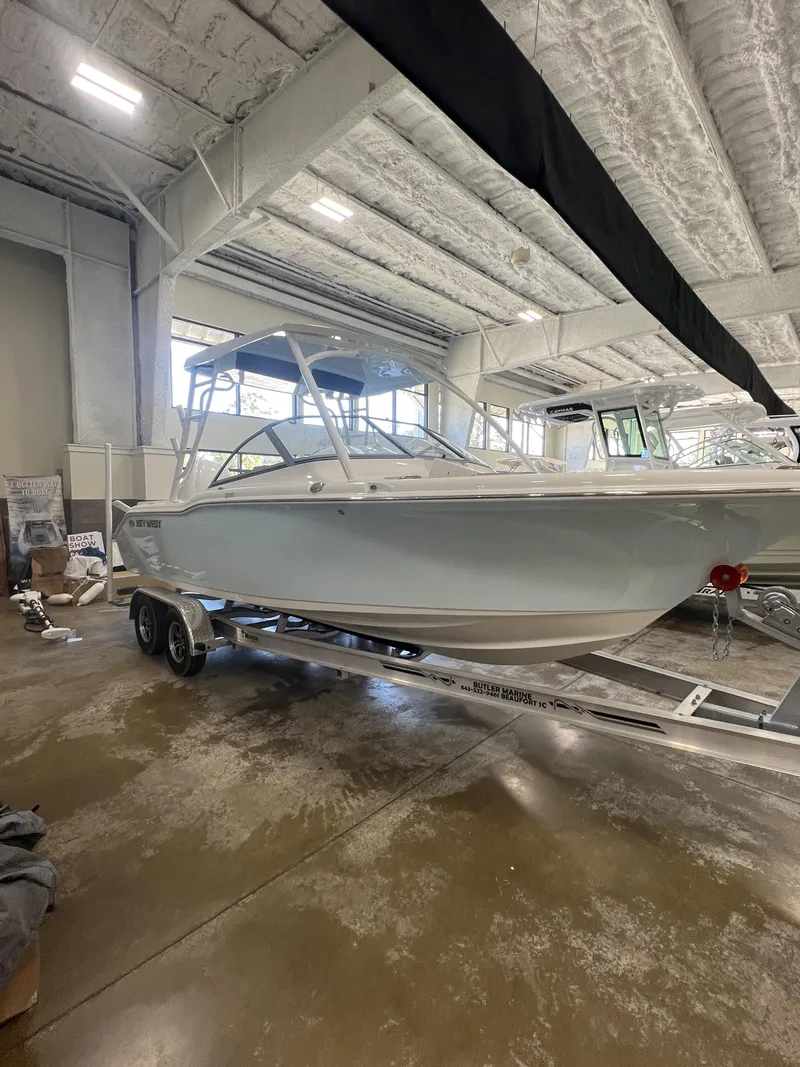 Slide: The Image of 2025 Key West Dual Console 239DFS boat on trailer in indoor showroom. - 1