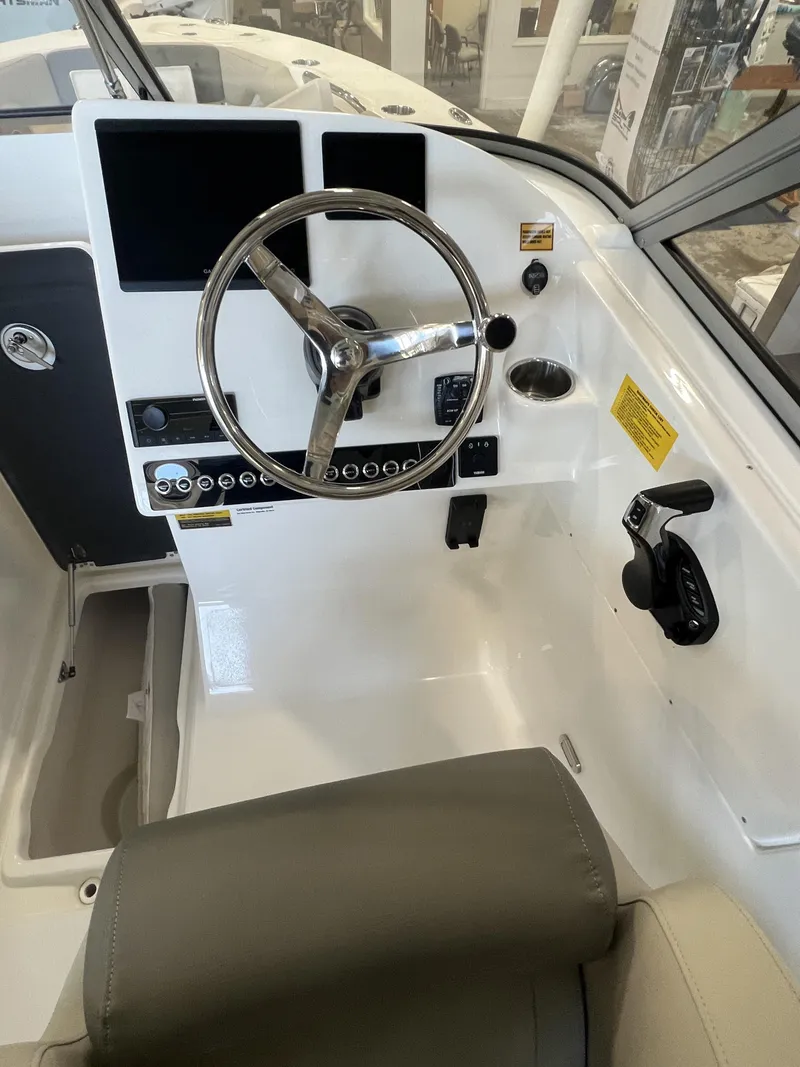 Slide: The Image of 2025 Key West Dual Console 239DFS boat cockpit with steering wheel and controls. - 5