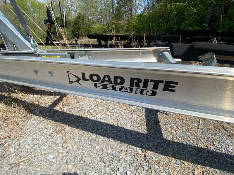 Slide: The Image of Load Rite trailer for 2021 Grady-White Freedom 275, parked on gravel with greenery background. - 36