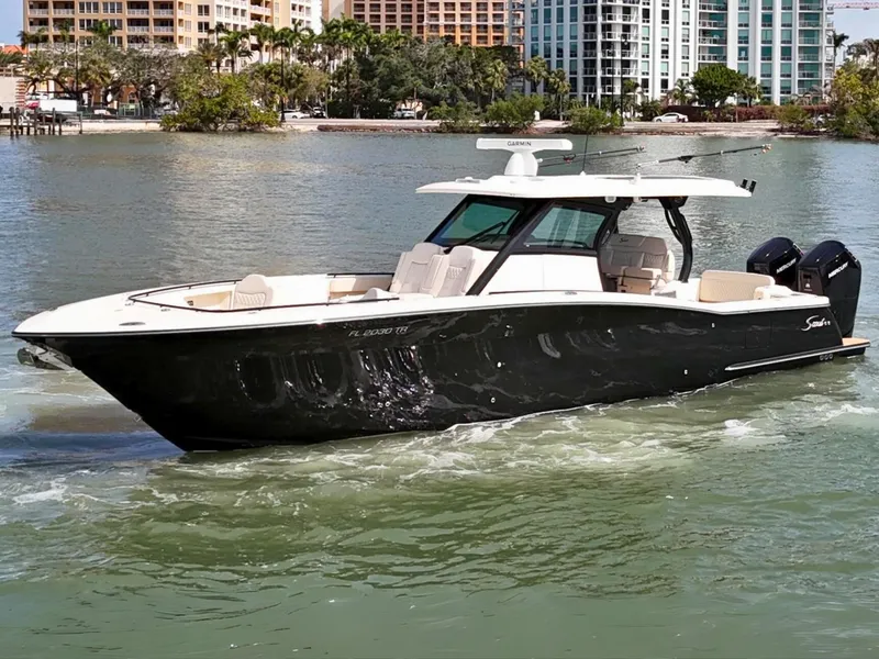 The Image of 2024 Scout 377 LXF boat cruising on water near urban skyline. - 0