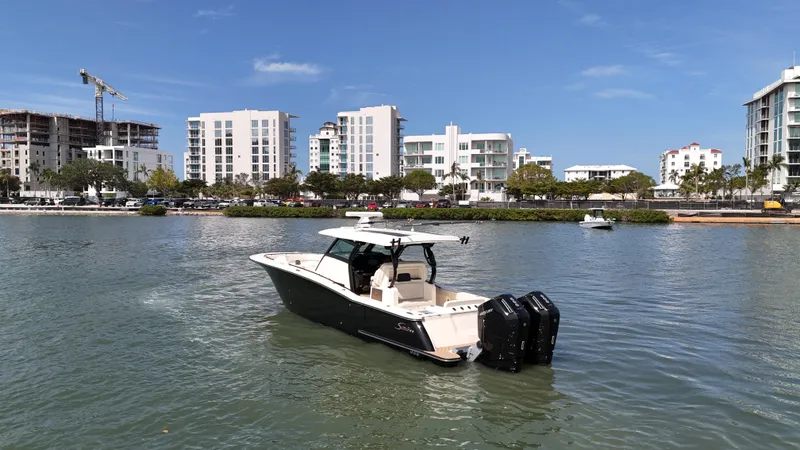 Slide: The Image of 2024 Scout 377 LXF boat cruising in urban waterfront setting. - 2