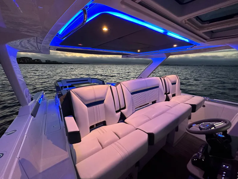 Slide: The Image of 2020 Tiara Yachts 43 LS interior with blue LED lighting, overlooking serene waters at dusk. - 12