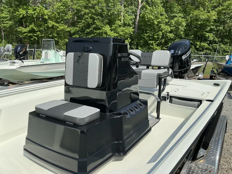 Slide: The Image of 2025 Excel Bay Pro 220 ELITE boat with seating, outdoors in a wooded area. - 7
