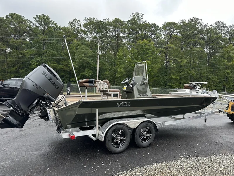 Slide: The Image of 2025 Excel New Bay Pro 230 boat on trailer with Suzuki outboard motor, parked outdoors. - 11
