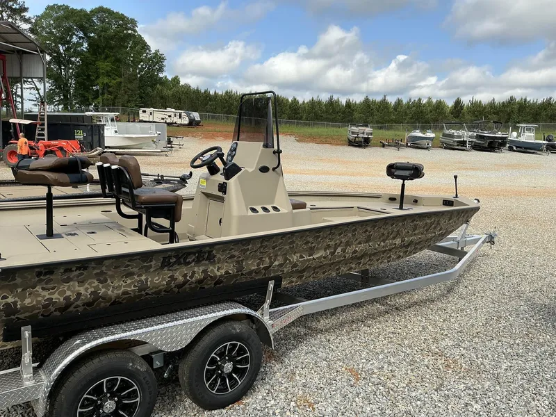Slide: The Image of 2025 Excel Bay Pro 220 ELITE boat on trailer, camo design, parked outdoors. - 4