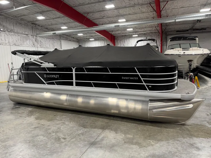 Slide: The Image of 2023 Sweetwater 2286 pontoon boat with black cover in indoor storage. - 9