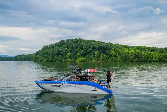 Slide: The Image of 2024 Yamaha Boats 222XD on a serene lake with lush green hills in the background. - 9