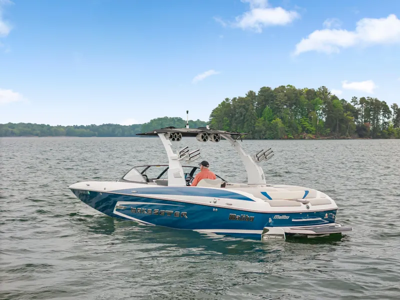 Slide: The Image of 2015 Malibu Wakesetter 24 MXZ boat on a lake with trees in the background. - 2