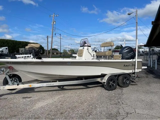 Slide: The Image of 2019 NauticStar 215 XTS boat on trailer, parked outdoors under a clear blue sky. - 1