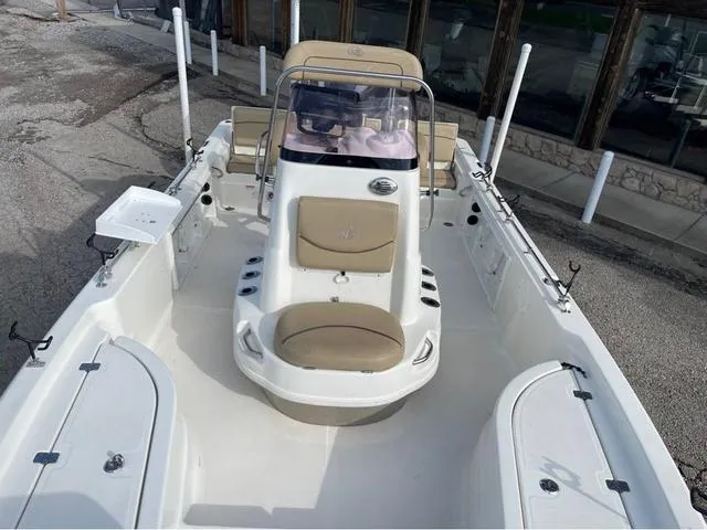 Slide: The Image of 2019 NauticStar 215 XTS boat with beige seating and center console, docked outdoors. - 8