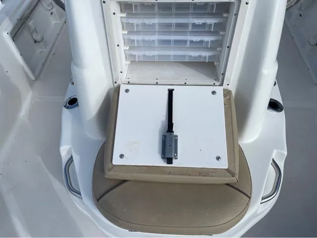Slide: The Image of 2019 NauticStar 215 XTS boat storage compartment with tackle boxes and cushioned seat. - 9