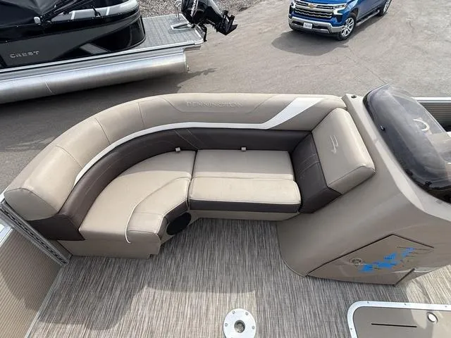 Slide: The Image of 2020 Bennington 22 SSX boat interior with beige and brown seating, docked near vehicles. - 10