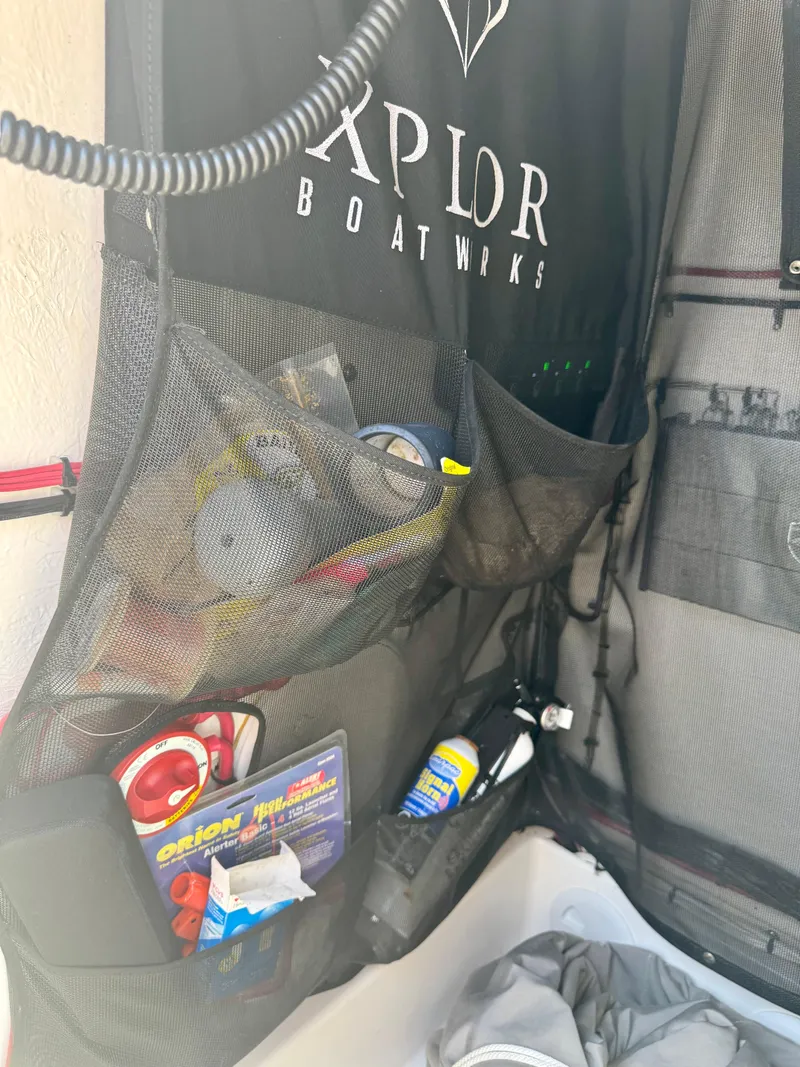 Slide: The Image of Storage compartment on a 2022 Xplor x24 Andros Mercury boat, holding various boating accessories. - 25
