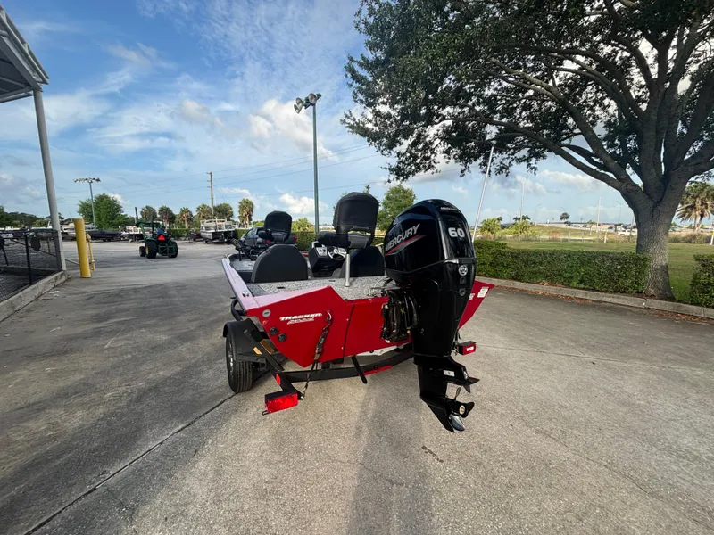 Slide: The Image of 2025 Tracker Pro Team 175 boat with Mercury engine, parked outdoors under a clear sky. - 2